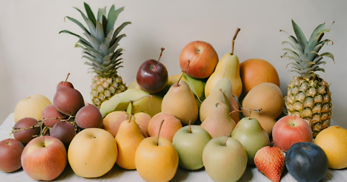 A colorful variety of fruits, including grapes, apples, and bananas, rest on a wooden table.